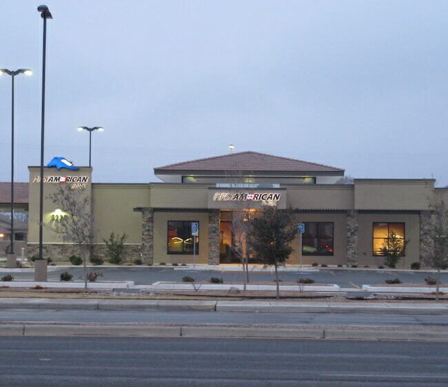Exterior view of a modern chase bank branch during twilight, featuring lit windows, a prominent logo, and a sparse, tree-lined landscape along a street.