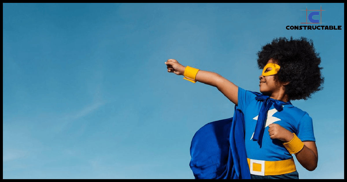 A young child dressed as a superhero, with a blue cape and mask, confidently points into the distance against a clear blue sky, depicting the rising construction costs.