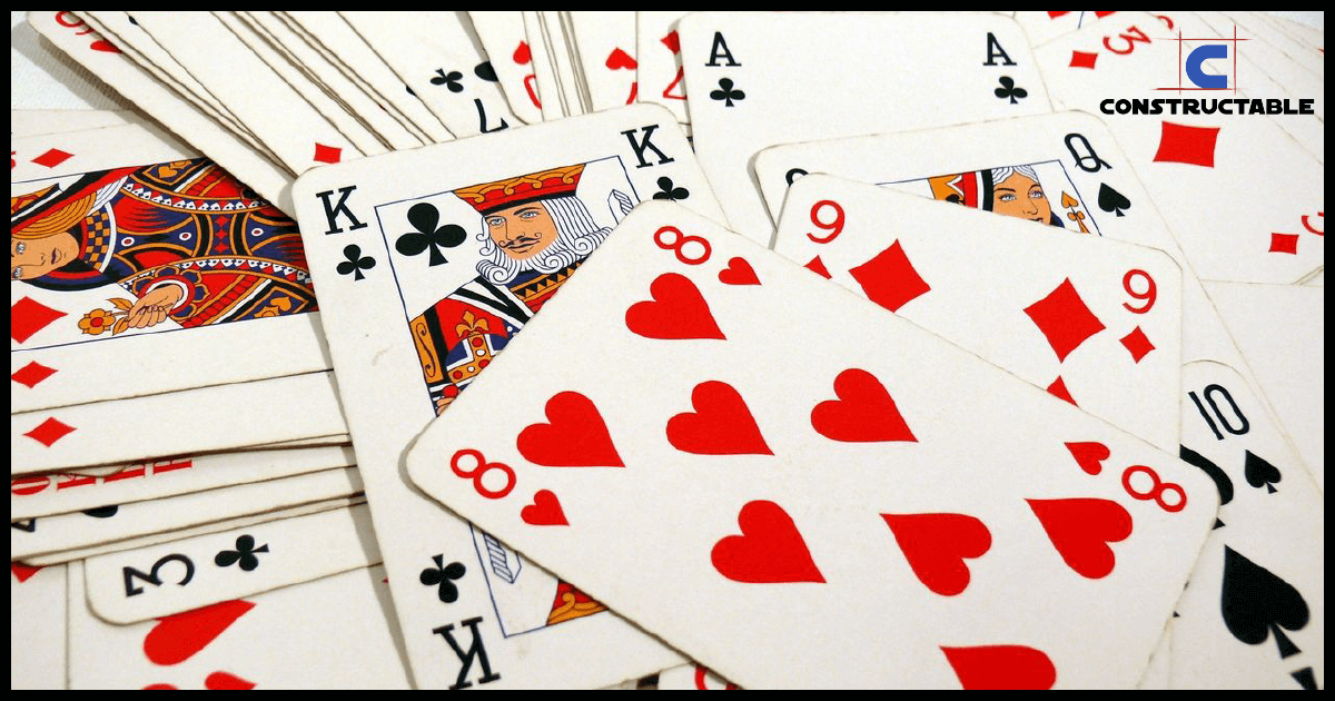 A scattered assortment of playing cards on a surface, prominently featuring various cards such as the king of clubs and the ace of spades, along with a sequence of hearts from 8 to 10.