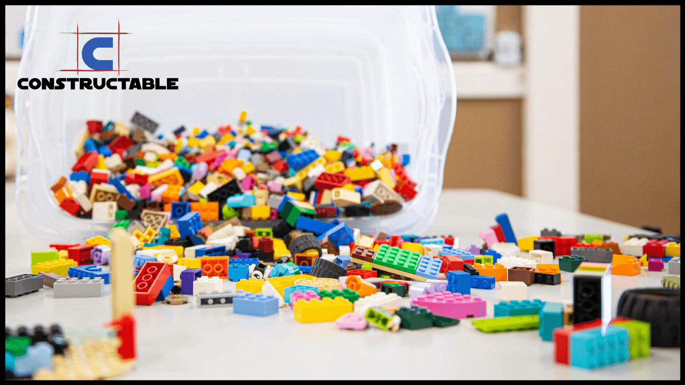 A colorful array of scattered lego bricks spills from an overturned plastic container onto a table, with a blurred logo reading "construction costs" in the background.