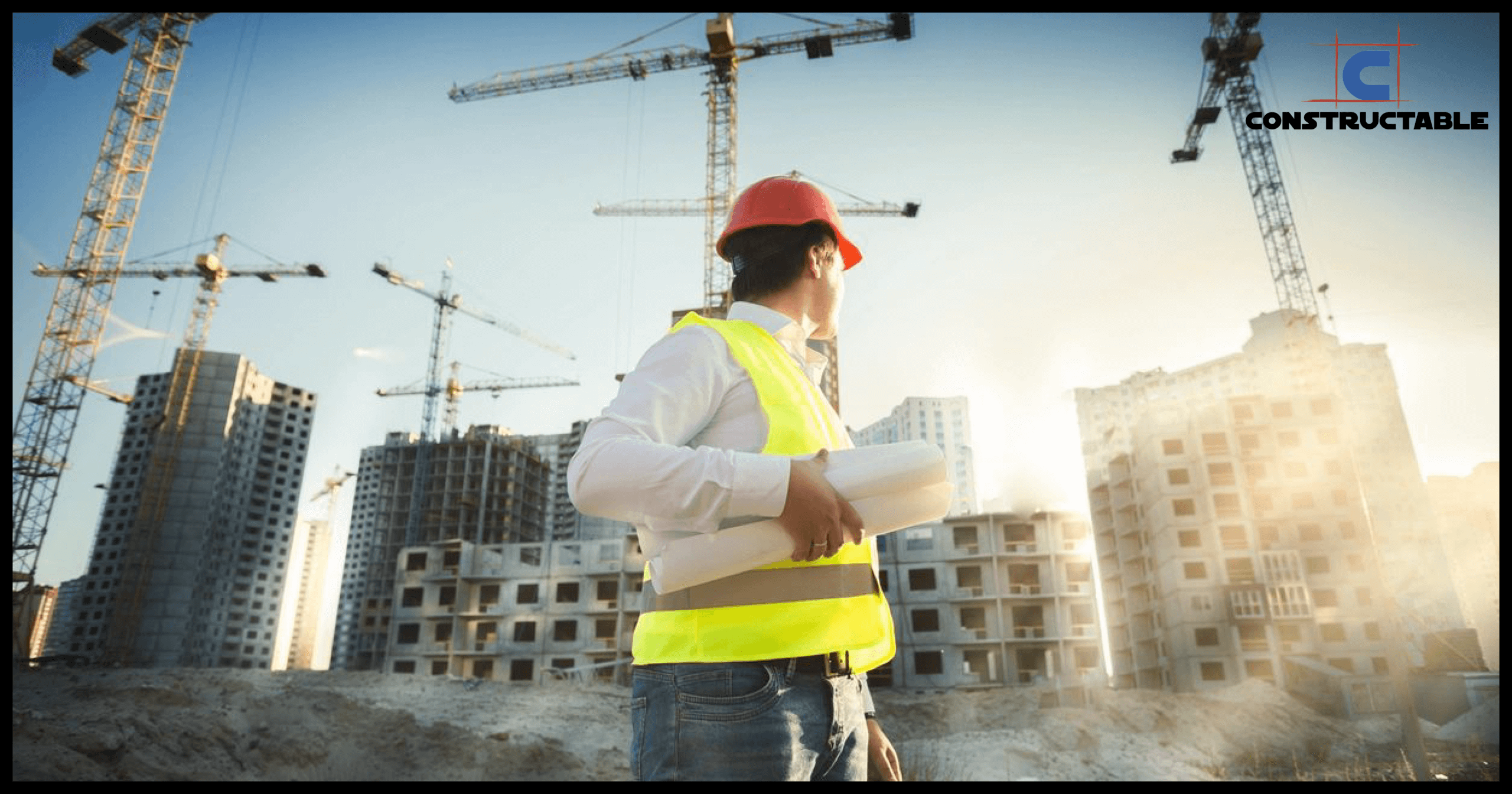 A construction worker in a red hard hat and reflective vest holds blueprints, looking at construction cranes and buildings against a sunny sky, contemplating the escalating construction costs.